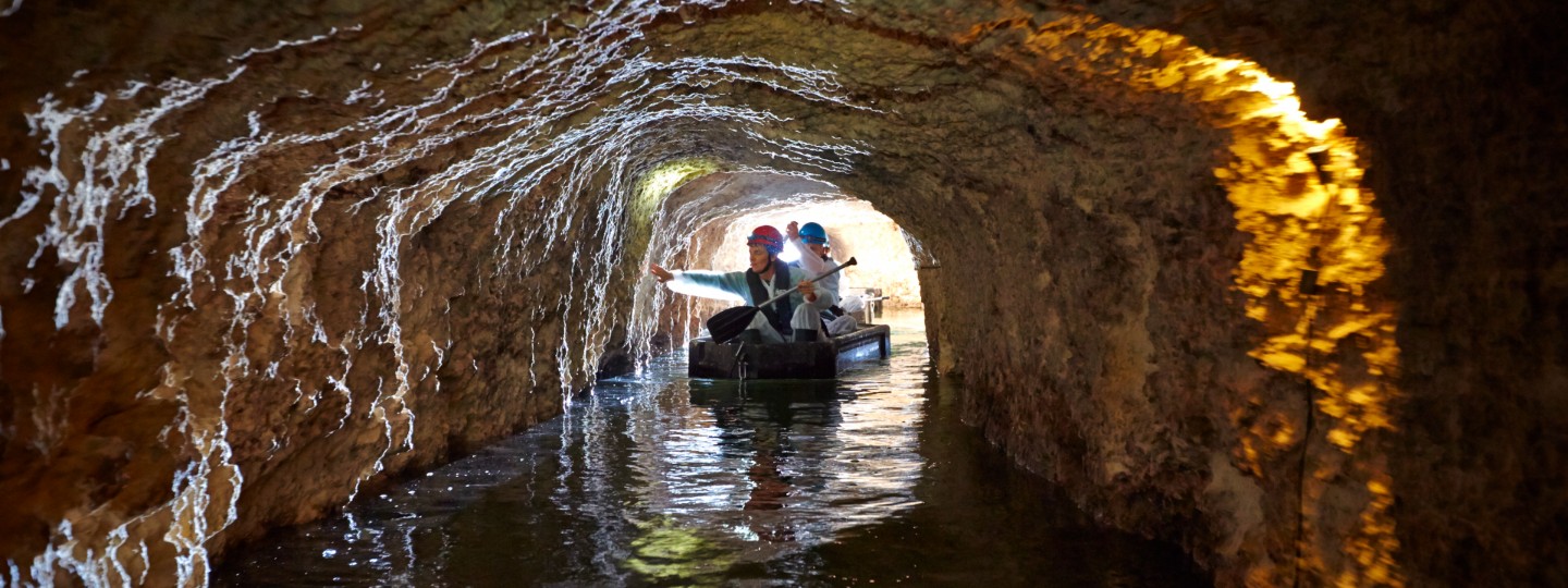two people paddle a kayak through water in a limestone tunnel