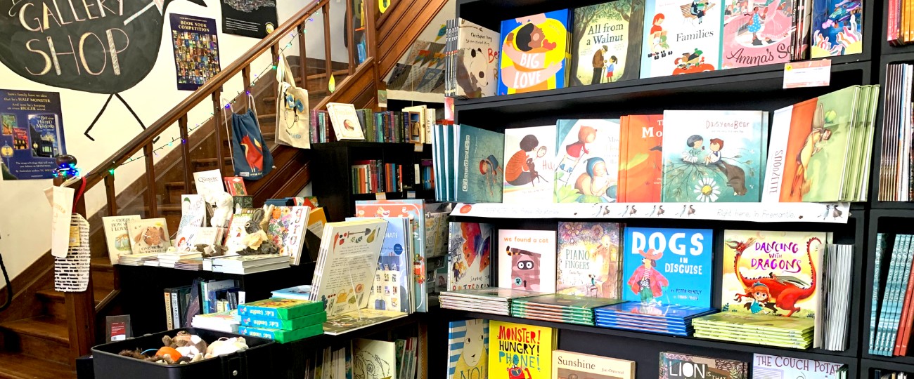 colourful books for children on dark bookcase with wooden staircase leading up to gallery