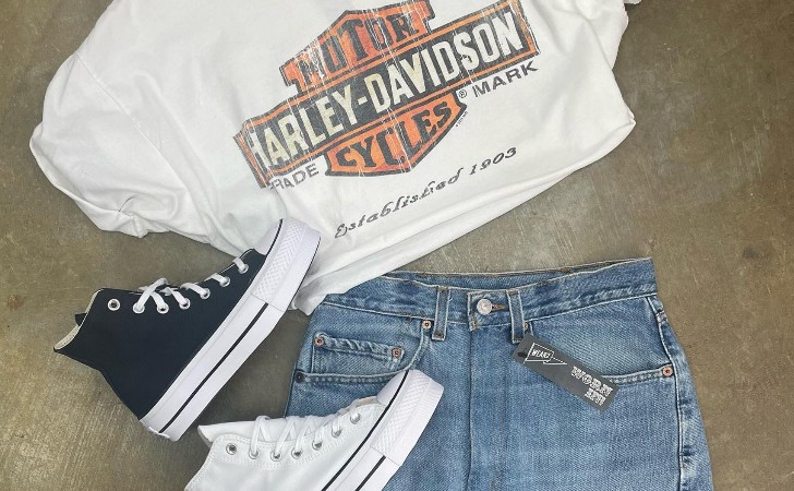 white Harley Davidson t-shirt, denim skirt and converse shoes flat-layed on polished concrete