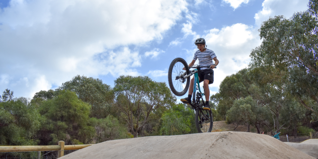 Rider at Booyeembara Park Mountain Bike Trail against big blue Fremantle sky in Perth, Western Australia