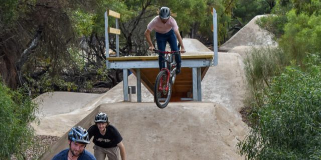 Three riders complete a jump at Booyeembara Park Mountain Bike Trail, Fremantle, Perth, Western Australia