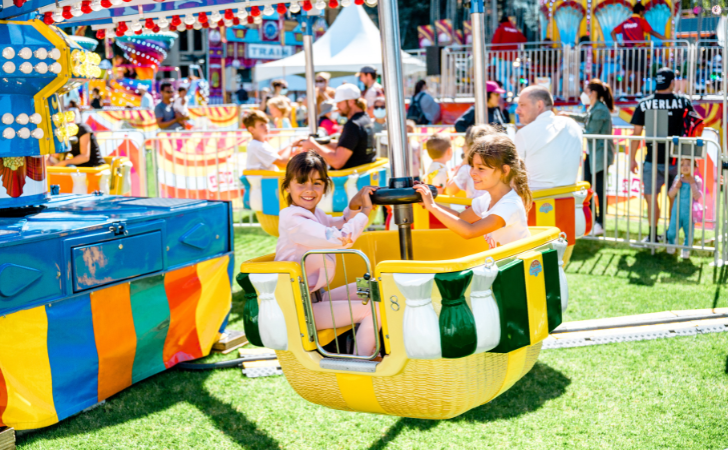 smiling children on colourful cup and saucer carnival fairground ride