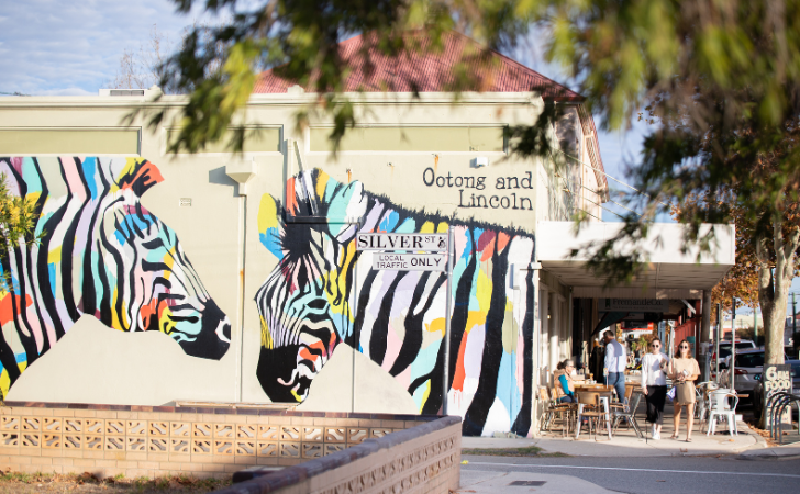 People stroll past two giant, colourful zebras on the wall of Ootong and Lincoln