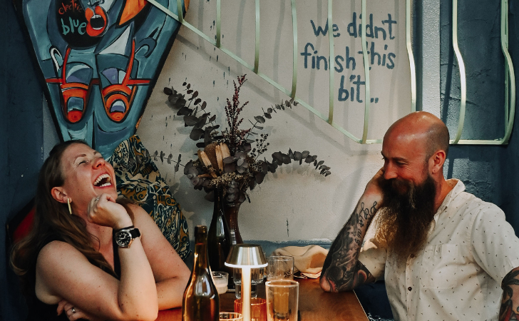 two people laugh and enjoy each other's company in a small bar