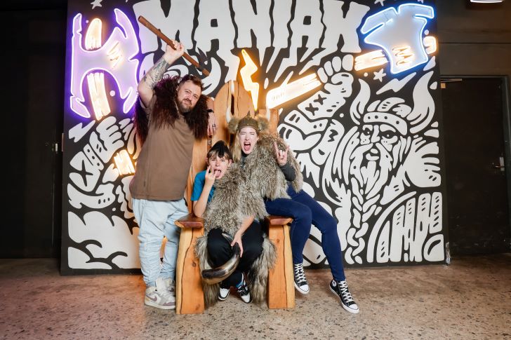 A young family pose with axes in front of the MANIAX Fremantle wall.
