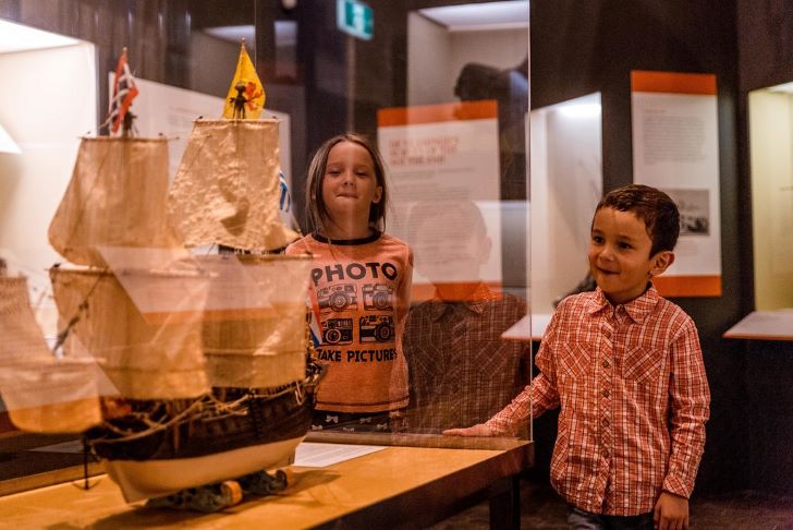 Two children admire a model of a ship.