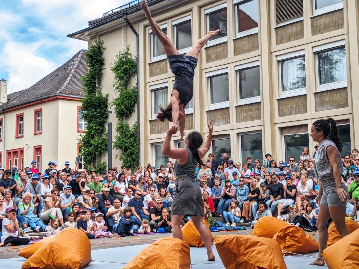 Three women leaping in front of a crowd with bean bags behind them.