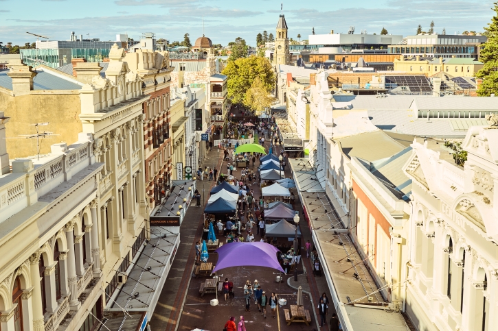 An overhead photo of a street on a sunny day with market stalls lining the road.