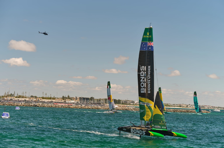 Artemis catamaran sailing in the Sail GP race with Fremantle and a helicopter in the background