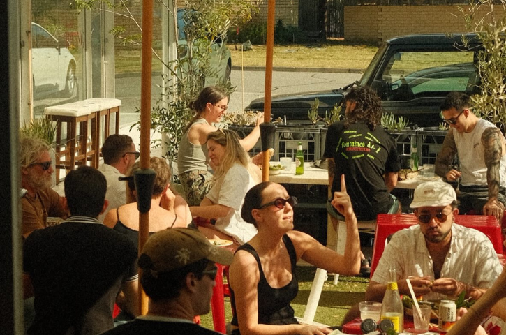 a crowd sitting outside a cafe eating and drinking 