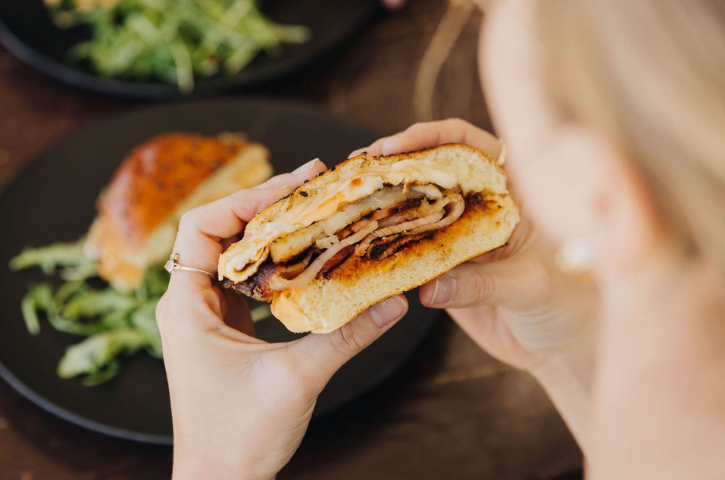 a breakfast sandwich in someone's hands with food in the background