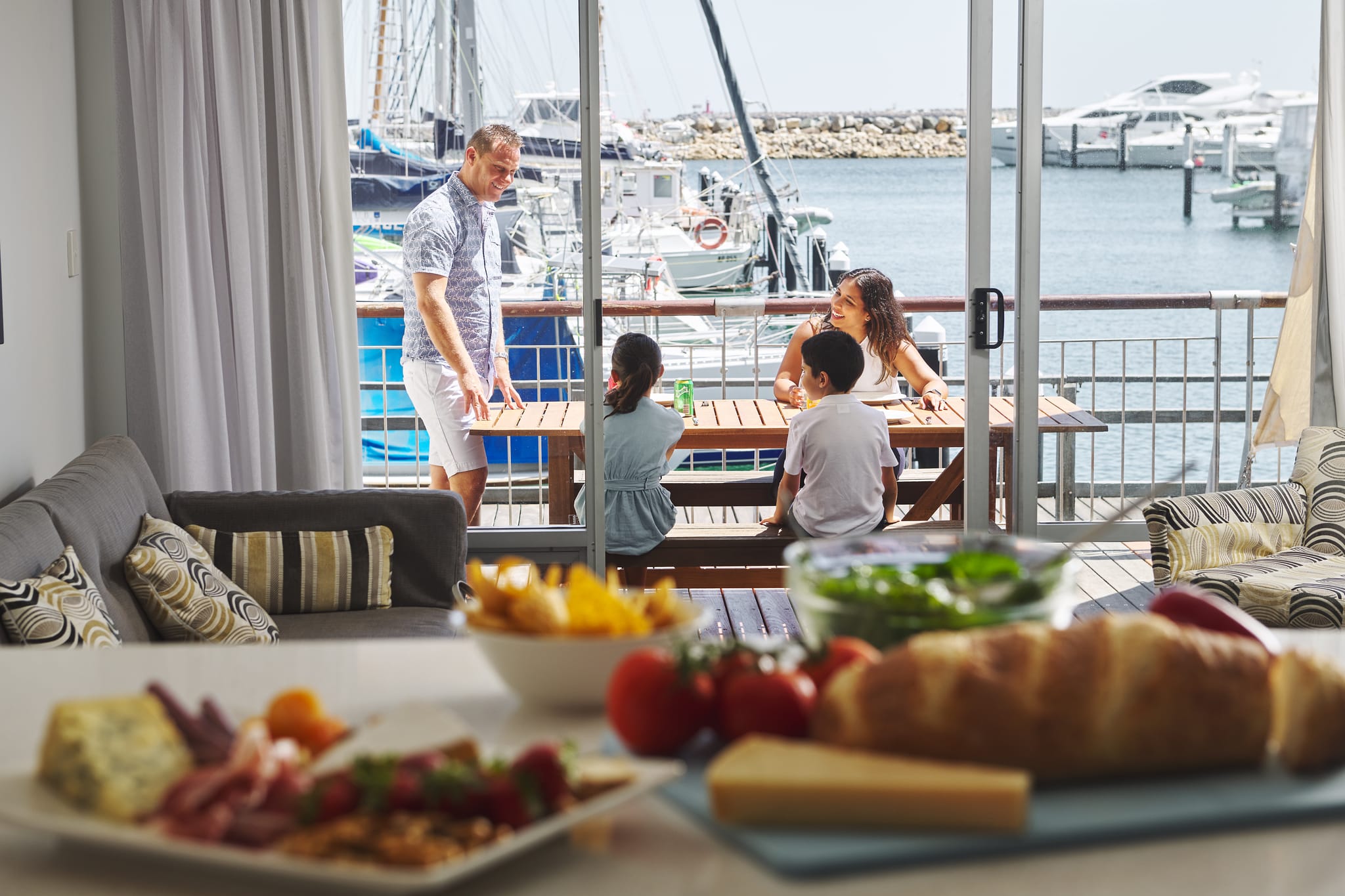 a family sitting outside a hotel room on the water