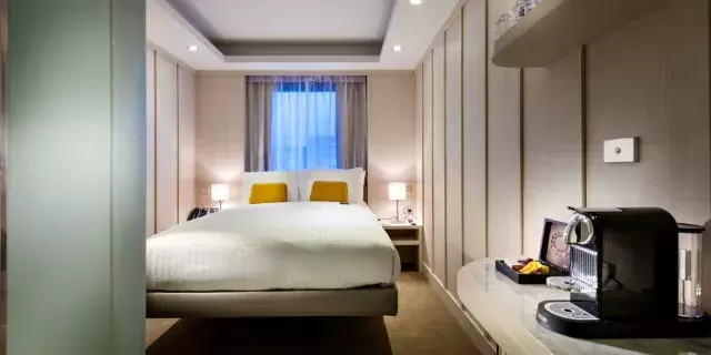 Interior of hotel room with large bed in front of a window