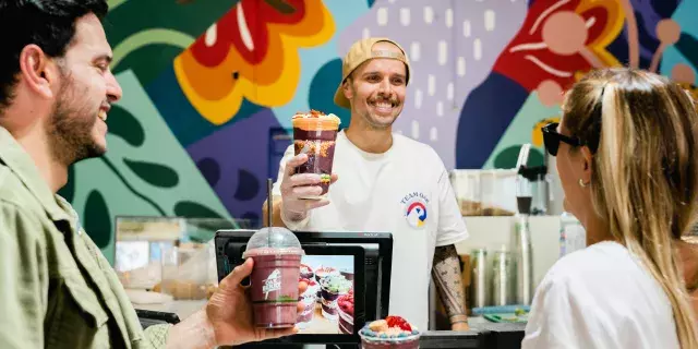 Male and female customer ordering from a friendly man behind the counter in backwards cap