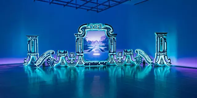 A blue room with a bright turquoise blue mirror installation depicting a portal to a blue and purple world.