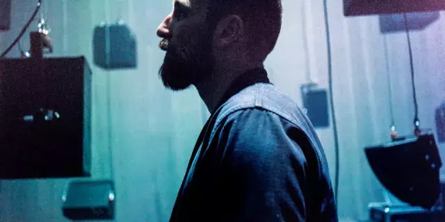 A man on side profile standing amongst black boxes