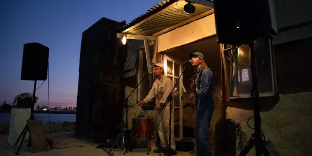 Two musicians playing keyboard and guitar outside a hut at Bathers beach