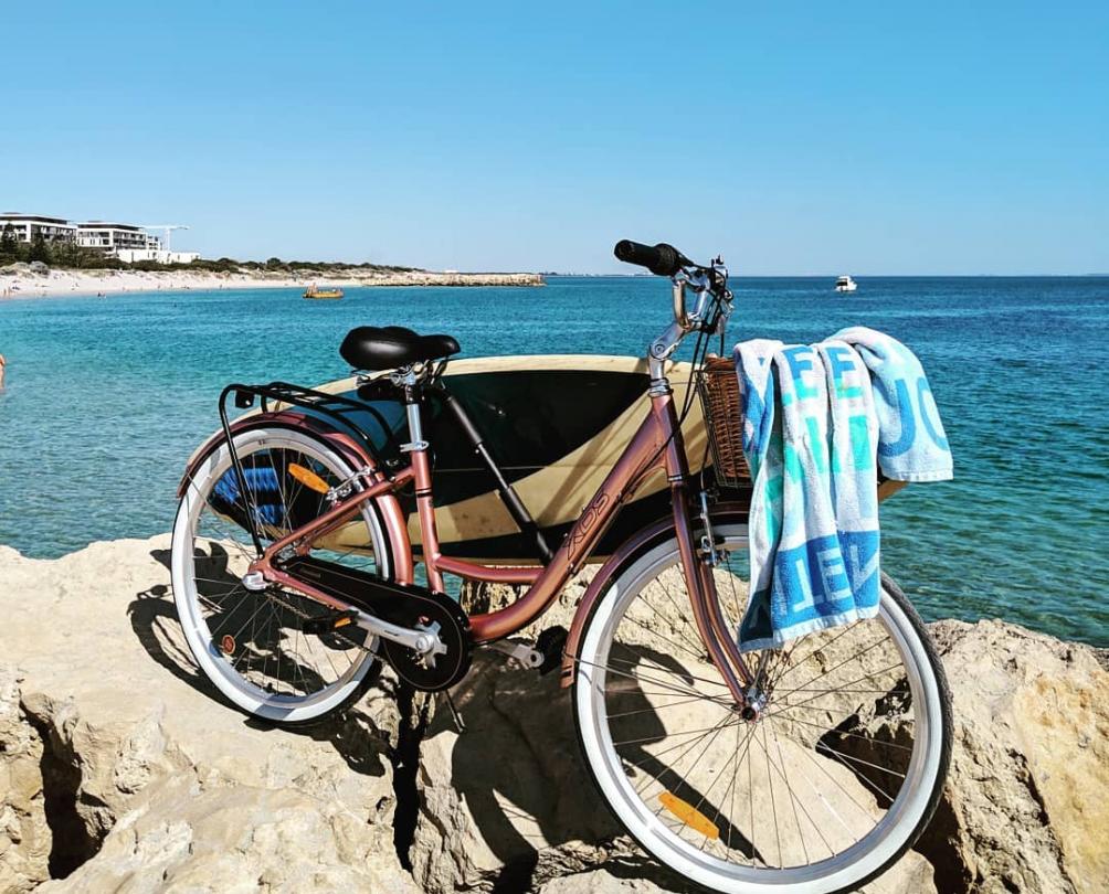 Bicycle at the beach with surfboard and towel 