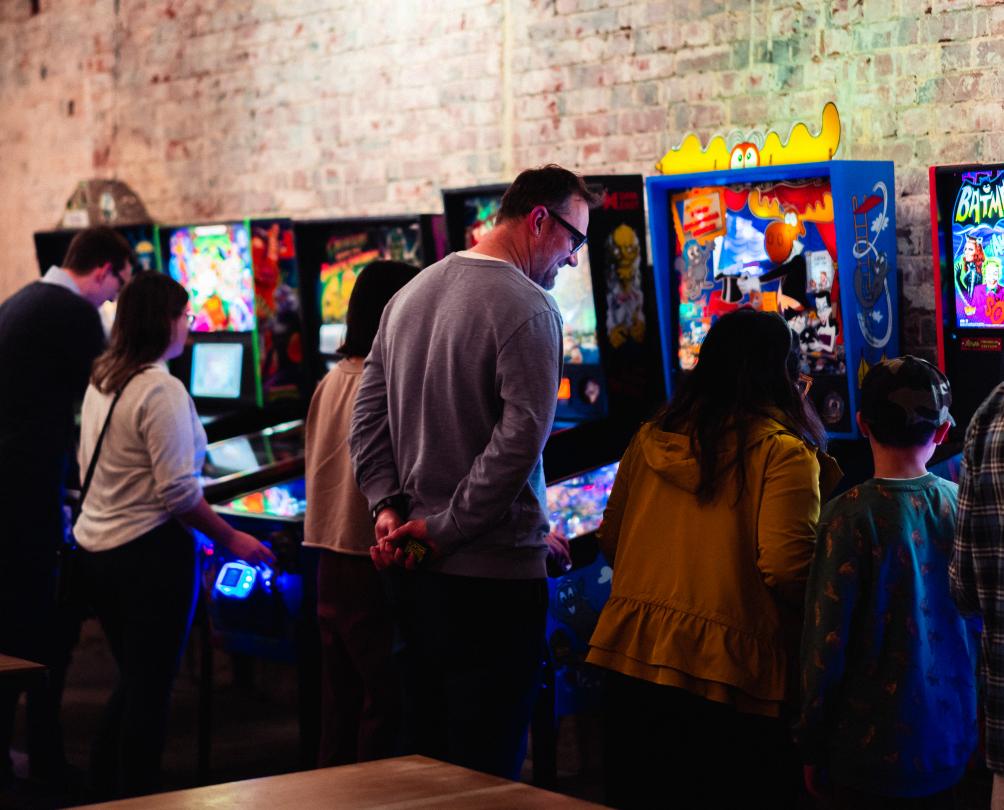Adults and children playing vintage video game machines at The Palace Arcade