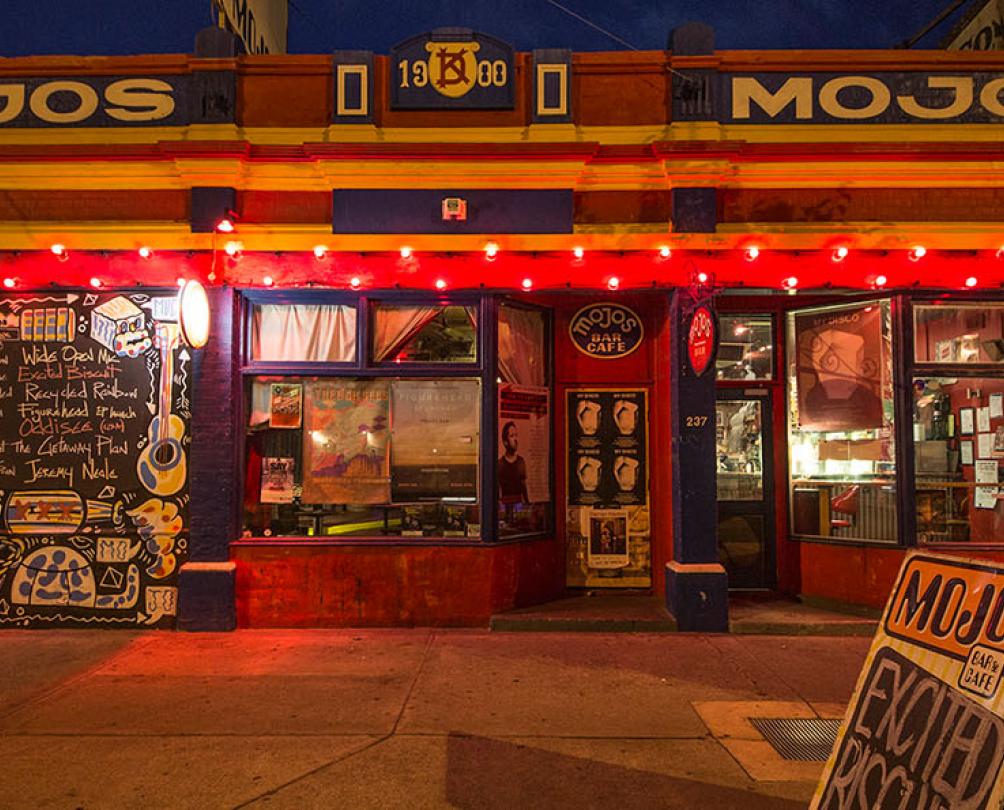 mojos building photographed at night. the building is bathed in a warm, soft red, orange glow of lights of the building.  