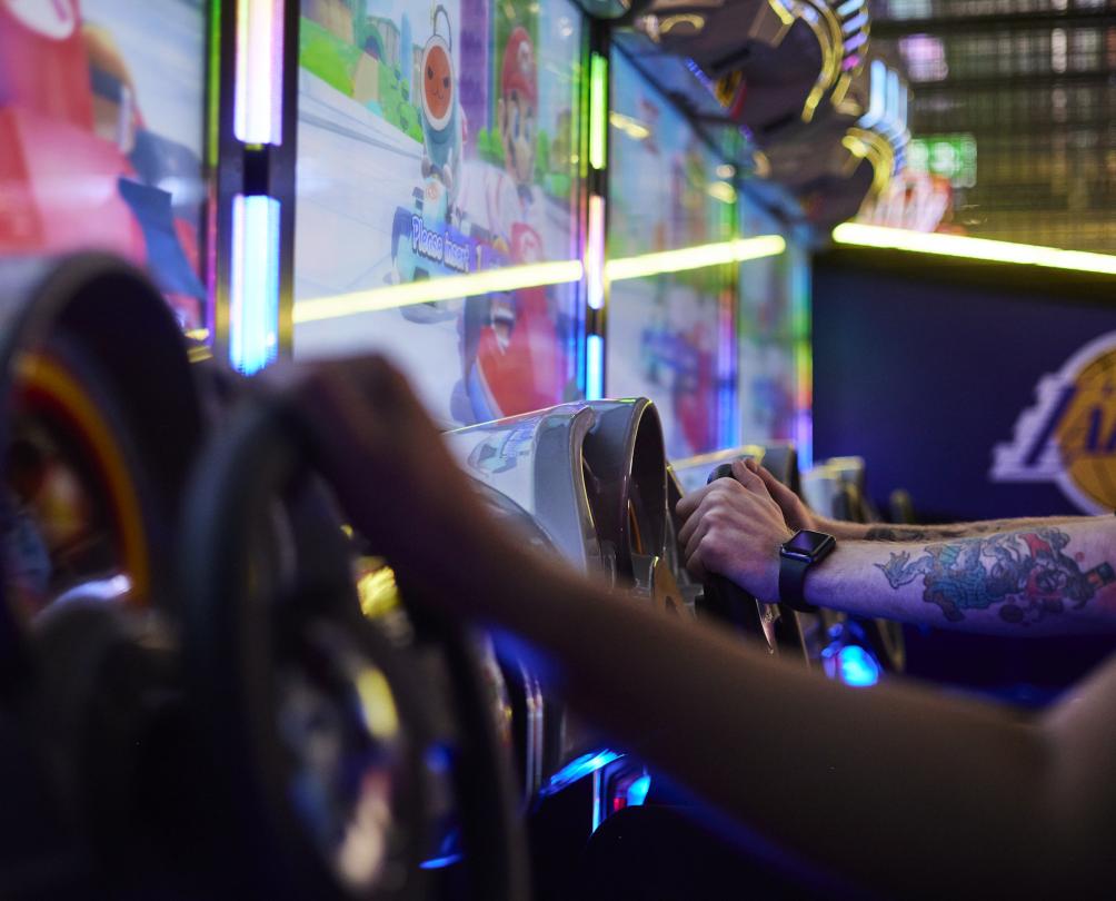 Arcade racing games with two players arms holding the steering wheels at B Lucky & Sons, FunLab Fremantle