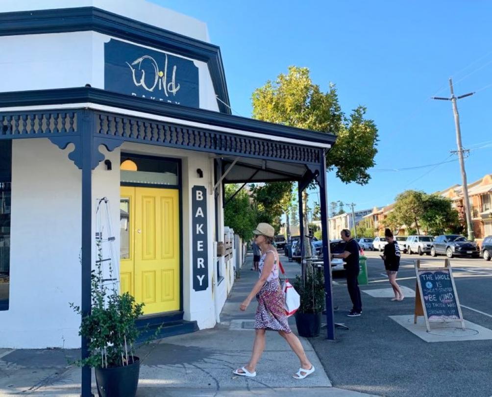 Person walking in front of the bright yellow front door of Wild Bakery in South Fremantle 