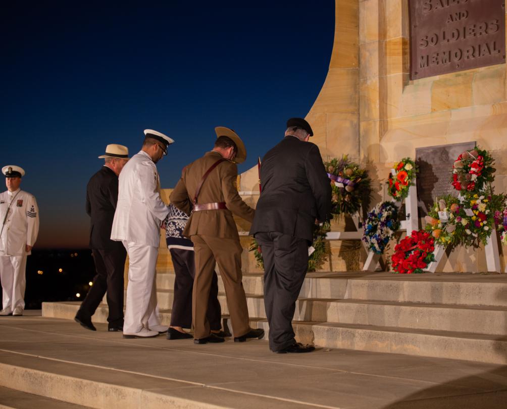 four service people lay wreaths at Anzac monument at dawn