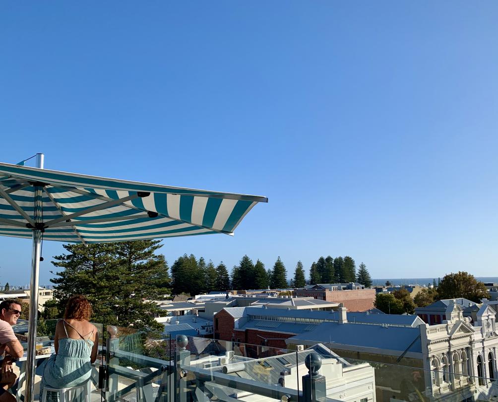 people looking out at blue sky view over city under striped umbrella