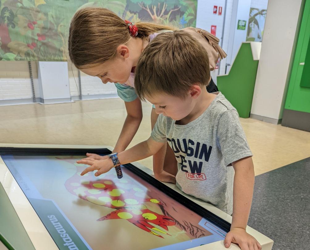 two children engage with a digital dinosaur game 