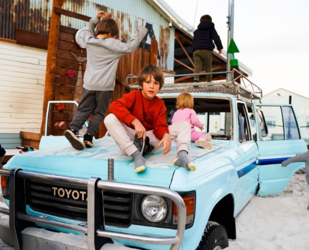 kids play on old blue toyota in giant sandpit playground