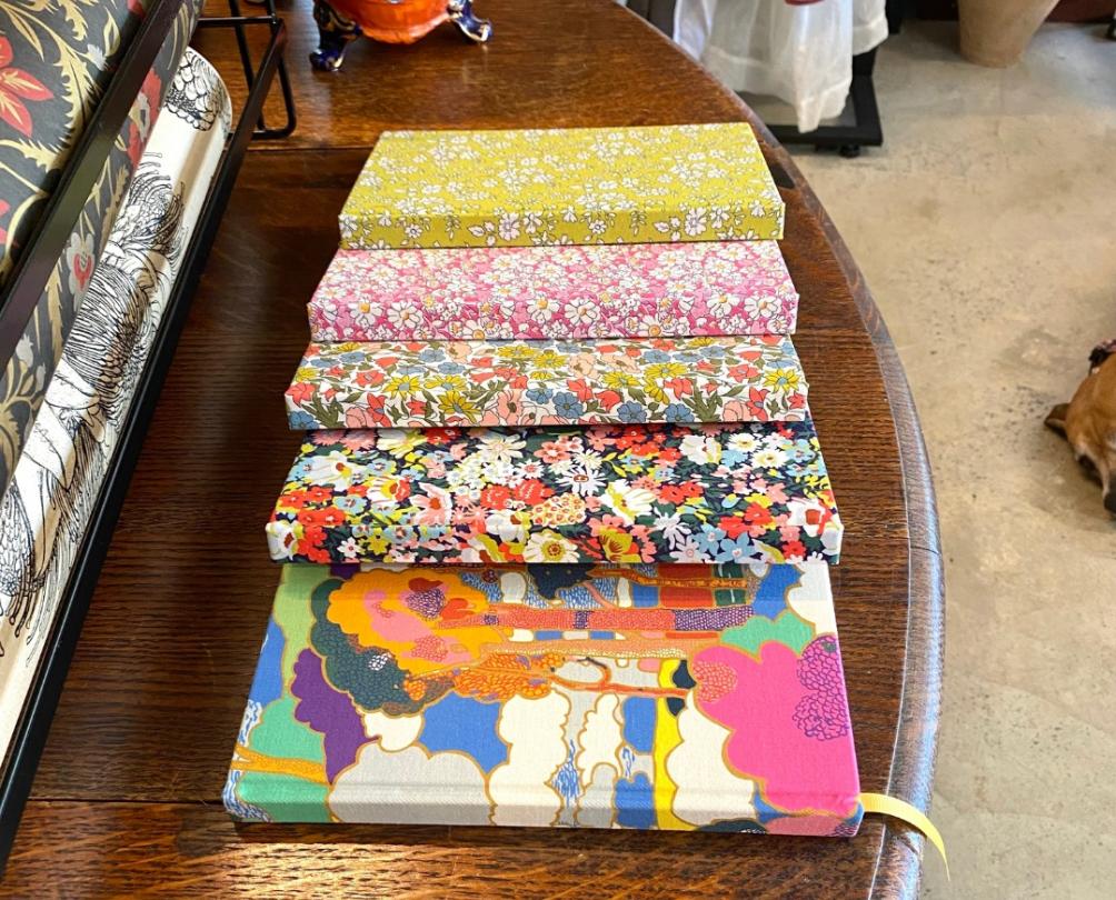 Coloourful hard cover journals lined up on a wooden table