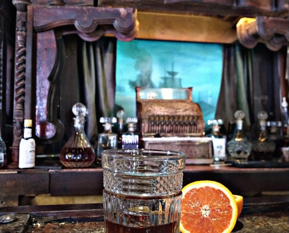 Old Fashioned rum cocktail on the bar next to an orange cut in half