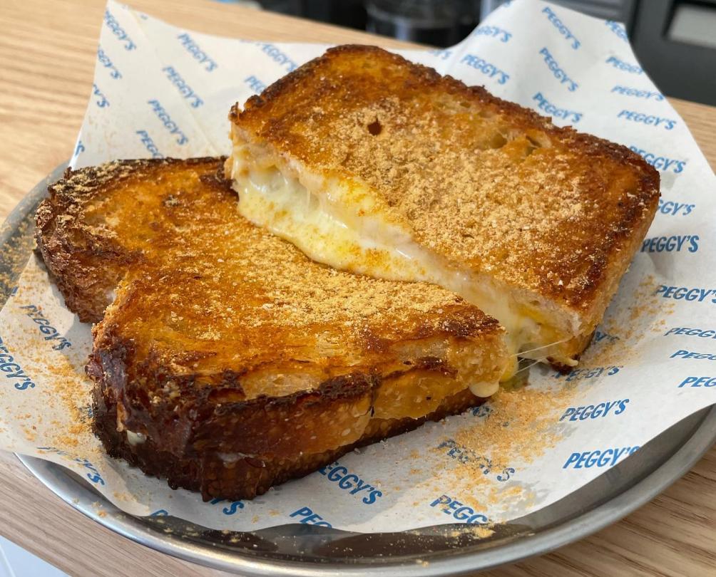 Toasted cheese sandwich on a plate with Peggy's branded paper underneath