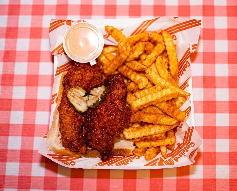 Chicken and chips on a paper plate against a red and white checkered tablecloth