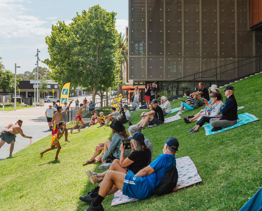 Traditional welcome ceremony in Walyalup Koort with public audience on grass slope