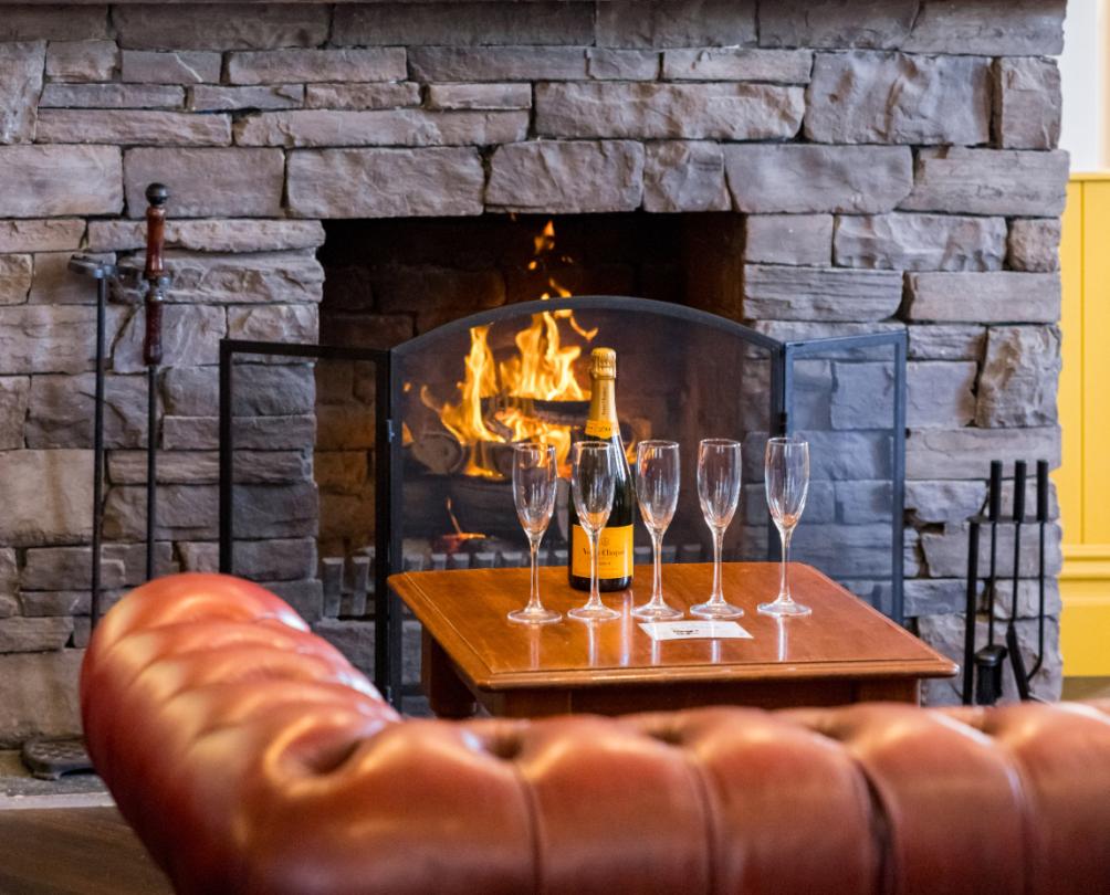 The Wray Hotel fireplace with a bottle of champagne and glasses on a wooden table