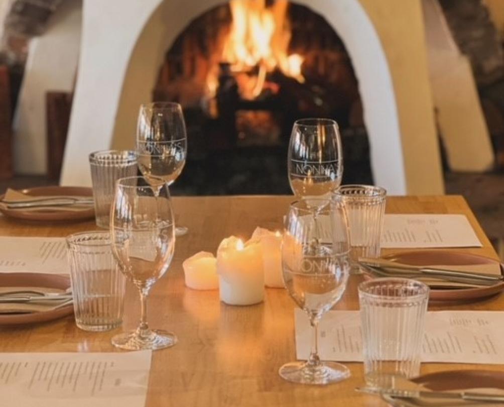 Table set for four in front of a crackling fire place at Nonna's Pizzeria & Cucina