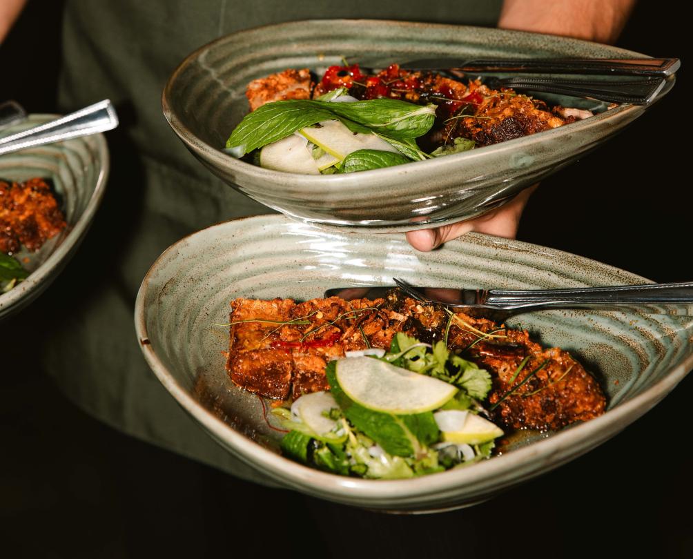 Close up of three dishes being carried by a waiter at Moon and Mary.