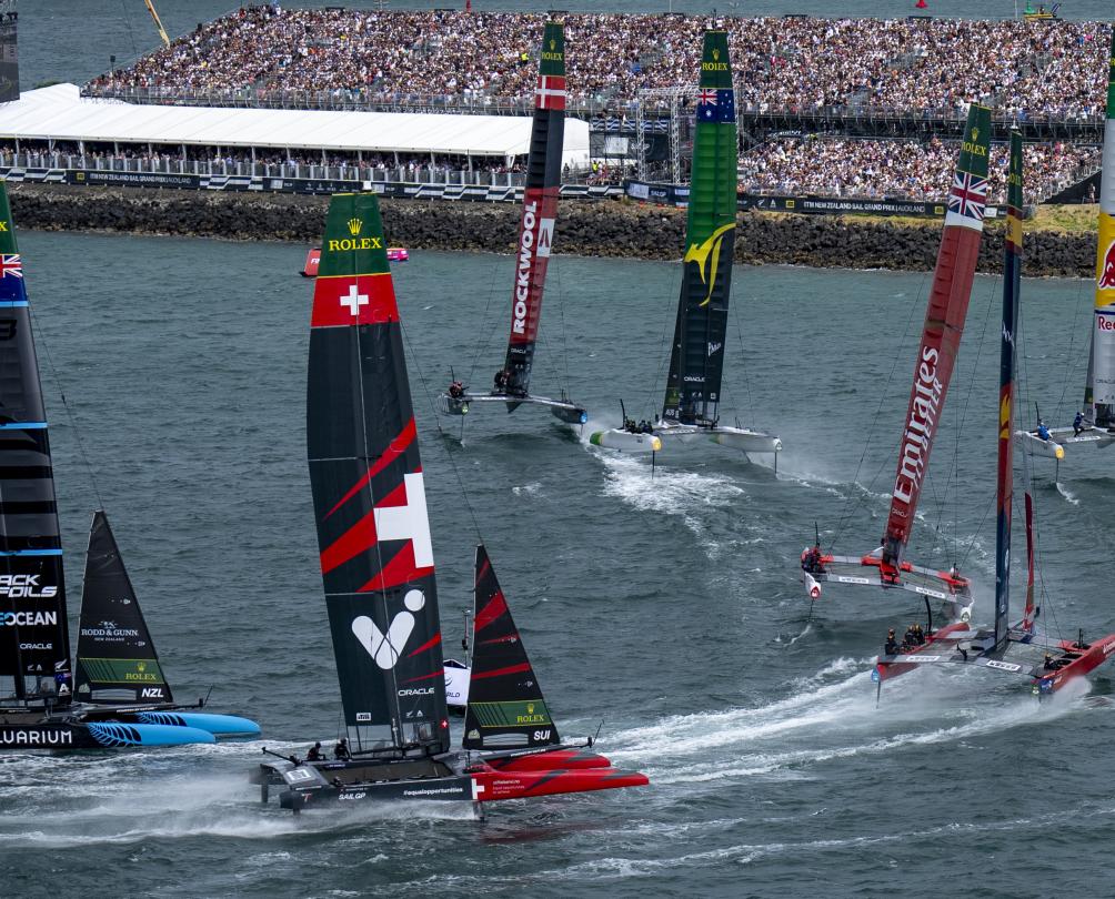 The fleet led by ROCKWOOL Denmark SailGP Team ahead of Australia SailGP Team and Red Bull Italy SailGP Team round the finish marker in front of the grandstand full of spectators on Race Day 2 of The Rolex SailGP 2025 Championship ITM New Zealand Sail Grand Prix in Auckland, New Zealand. 