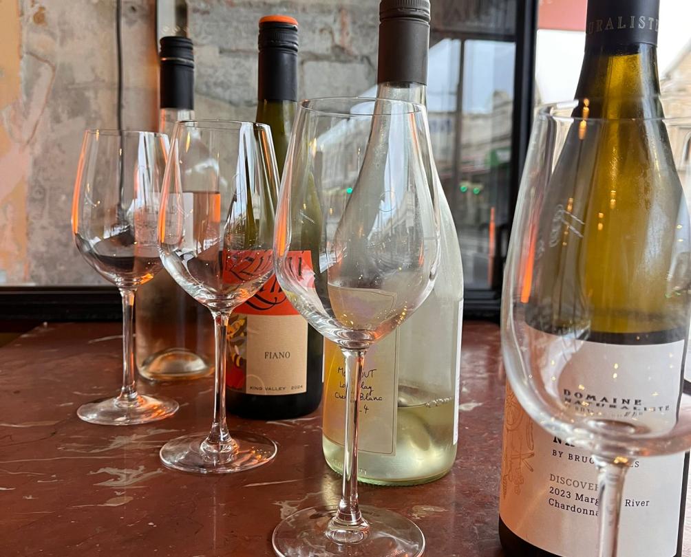 Wine bottles lined up with wine glasses.