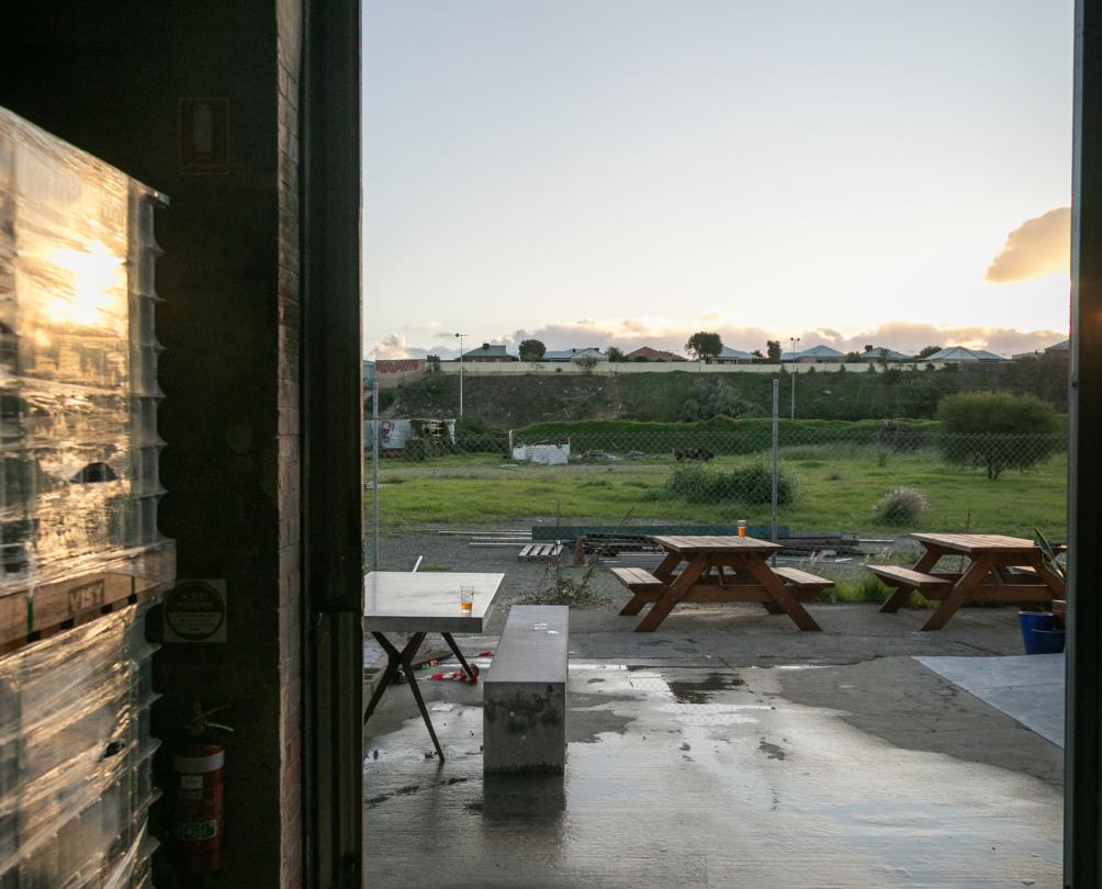 The interior of a venue looking through a big open shed door onto a grassed area with bench seating.