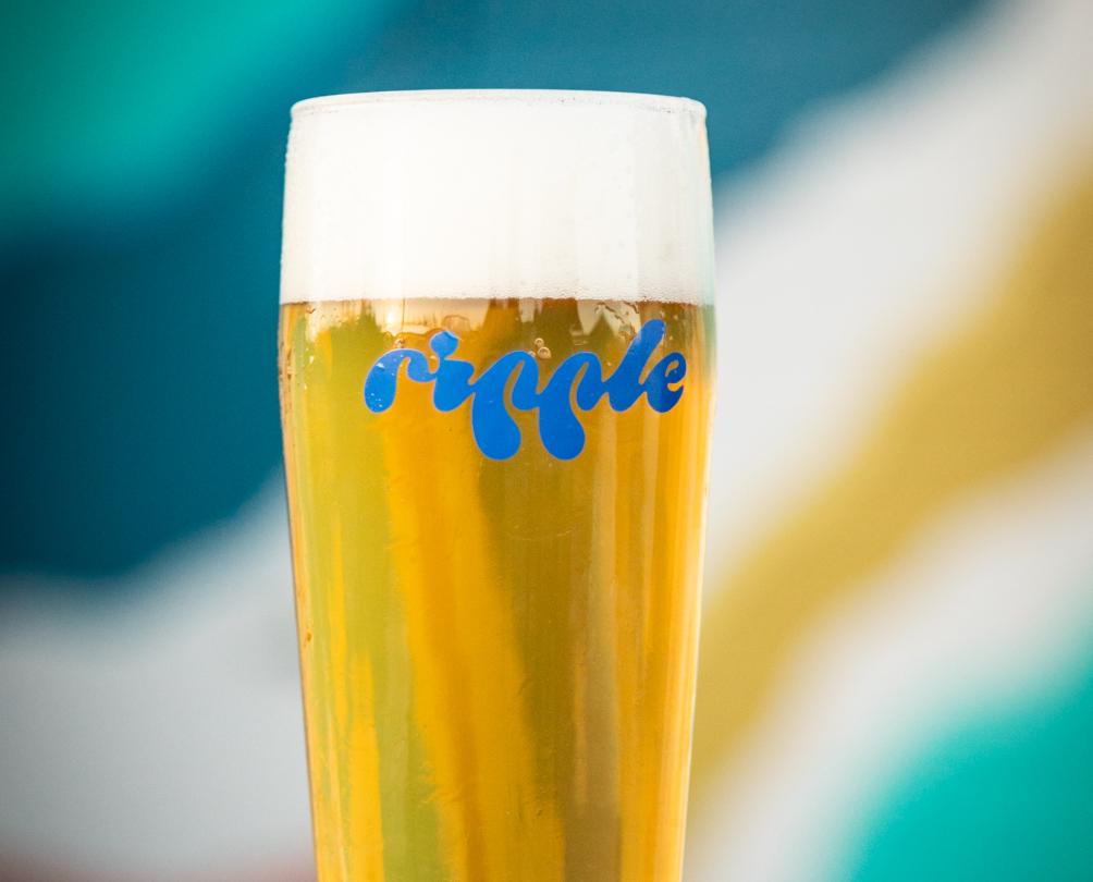 A pint of beer with the word ripple written on the glass in blue.