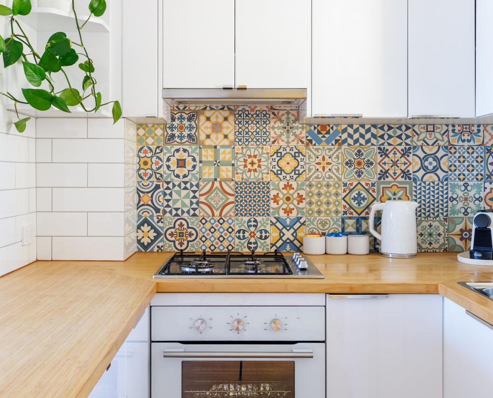 A kitchen with a colourful mosaic of tiles behind.