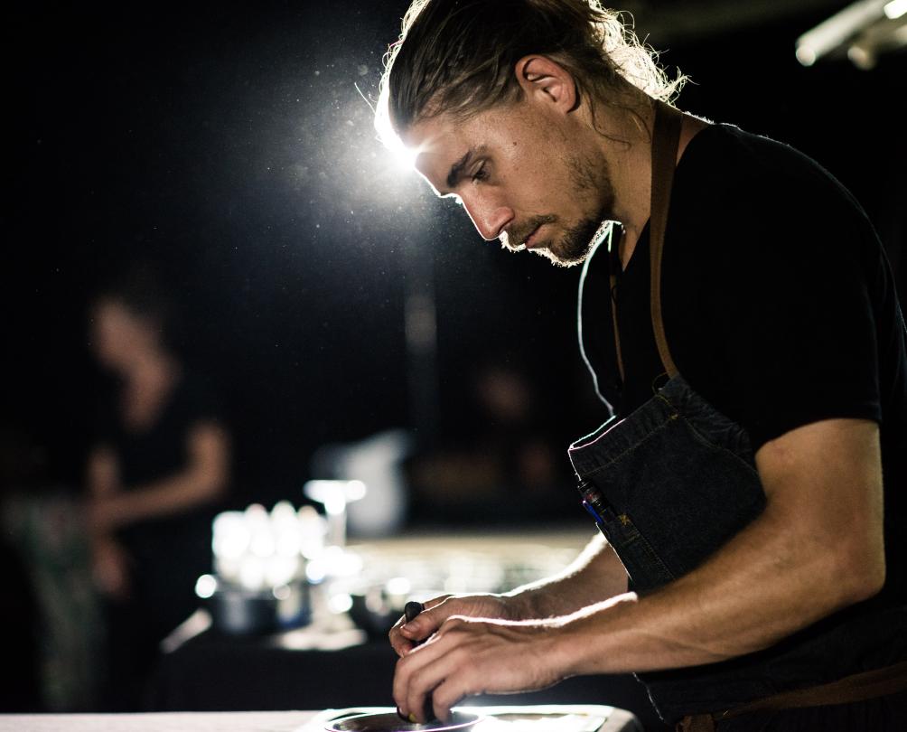 A chef prepares a meal at night under a bright light.