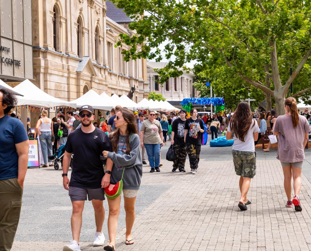 A city square filled with people and various stalls.