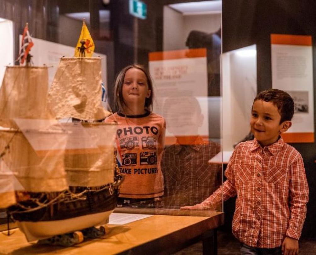 Two children admire a model of a ship.