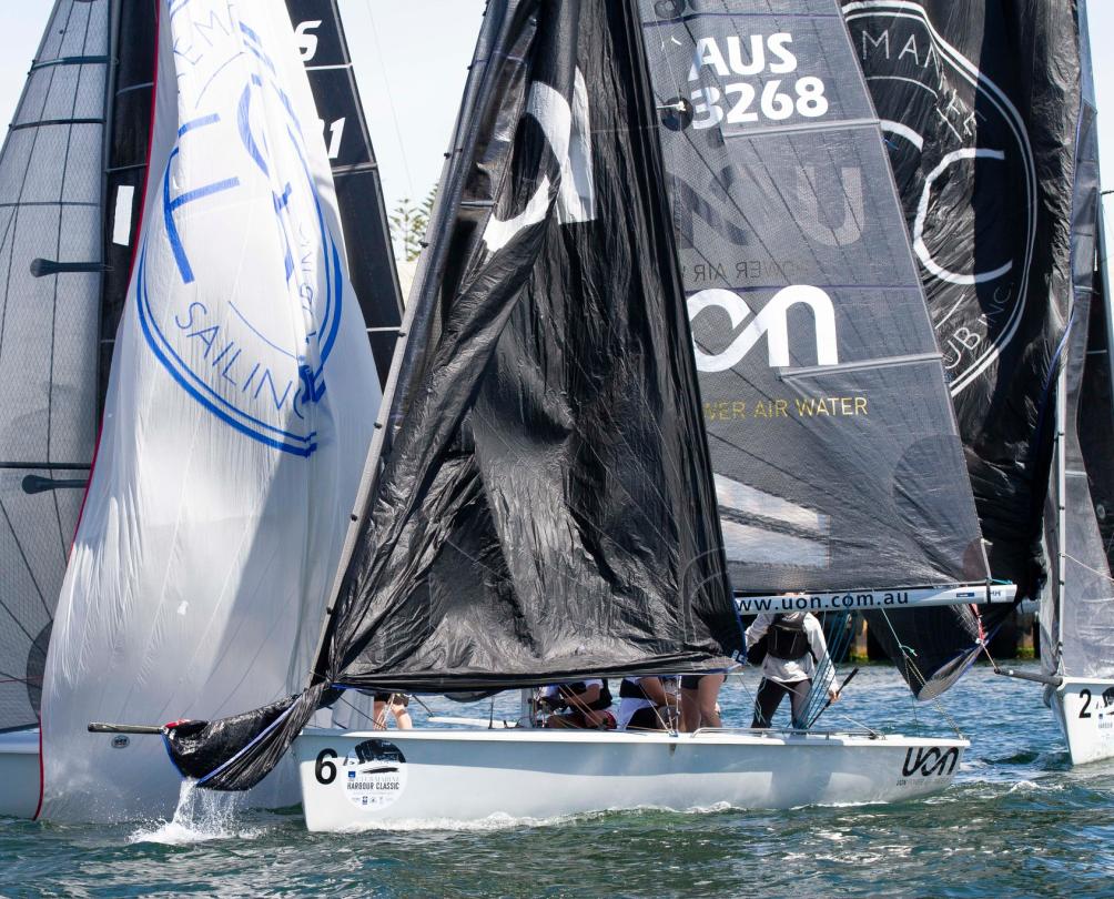 Close up of a several sailing boats huddled together with black sails.