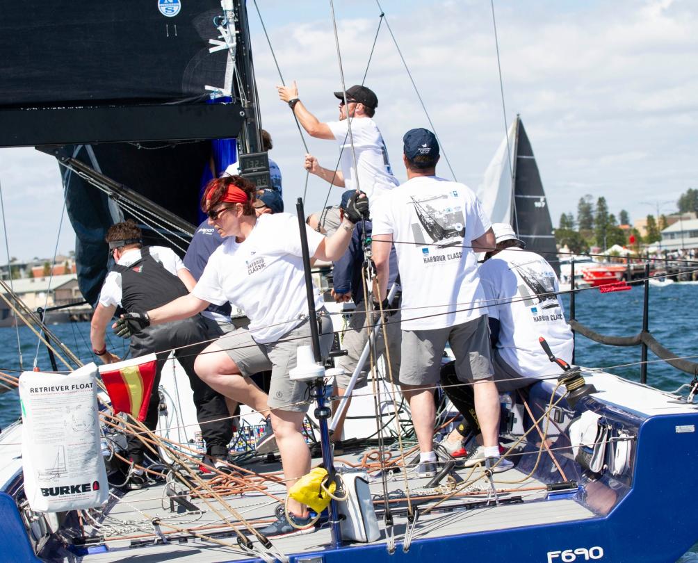 Several people on a sailing boat participating in a race.
