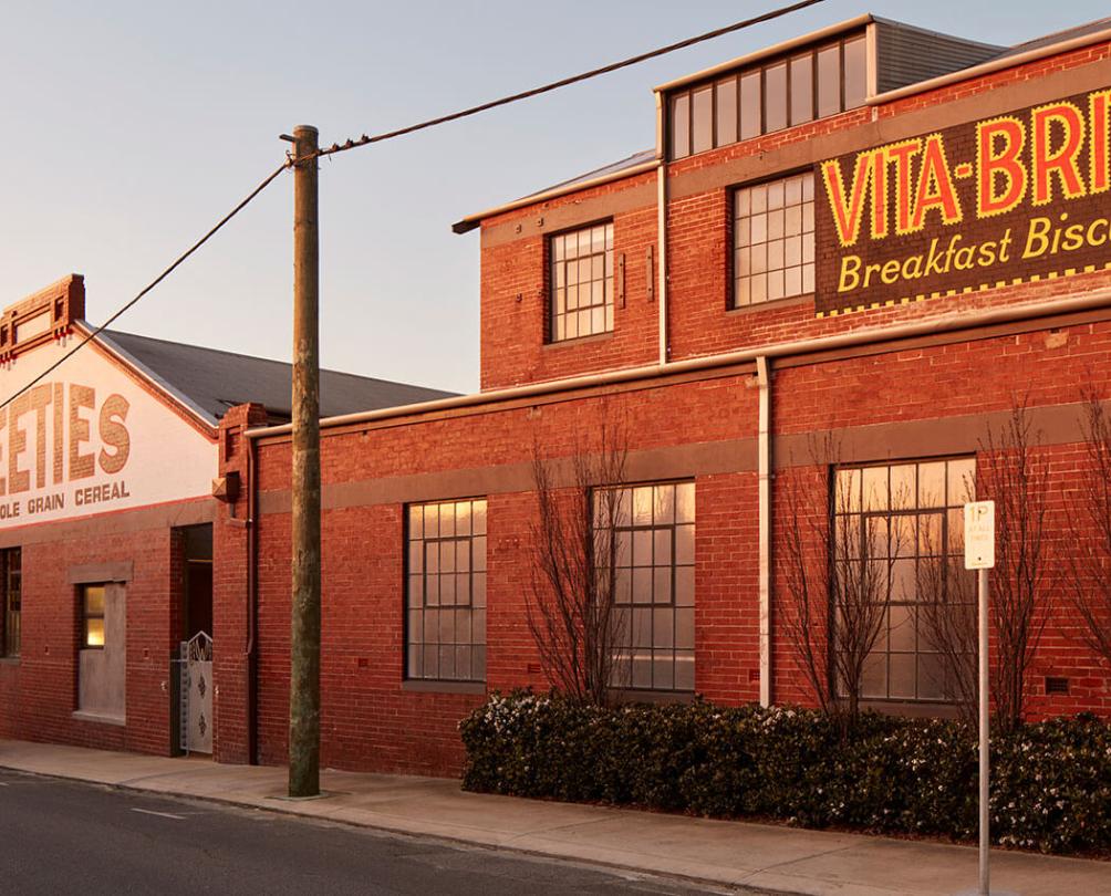 An old photo a red bricked building with the words 'Weeties' and 'Vita-brits Breakfast Biscuits' on it.