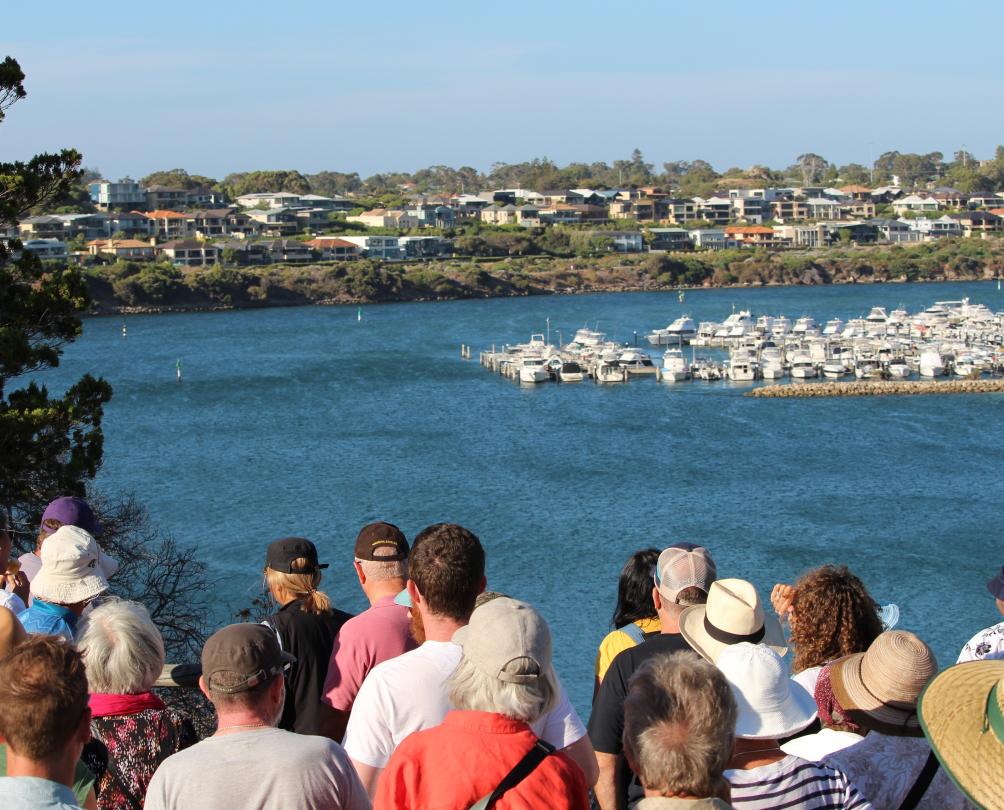A group of people look out into a bright blue bay.